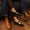 Pair of black suede Lola Mary Jane flats with gold buckles worn with denim jeans and brown leather boots.
