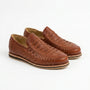 Pair of brandy brown woven leather huarache slip on shoes for men on a white background.
